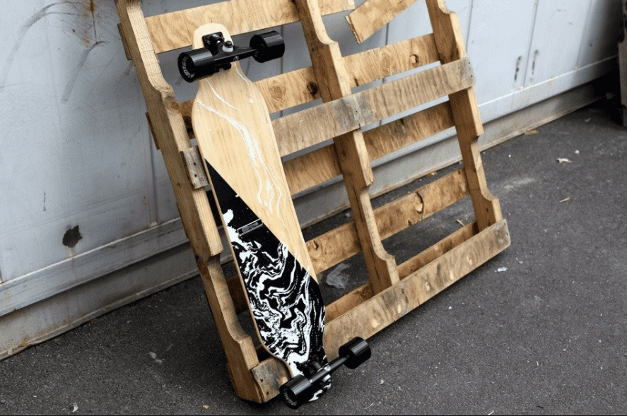 DB Longboard leaning on a piece of wood