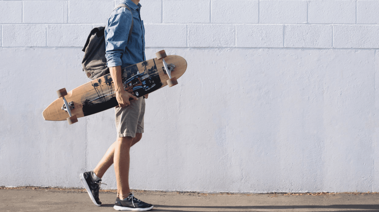 Man in side-view carrying his DB longboards